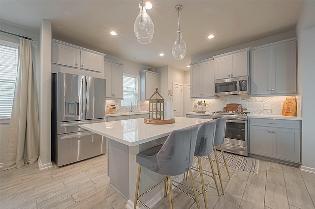 23611 Blackhaw Blossom Ln, Katy, TX 77493 - kitchen featuring appliances with stainless steel finishes, wood finish floors, light countertops, a kitchen island, and a breakfast bar