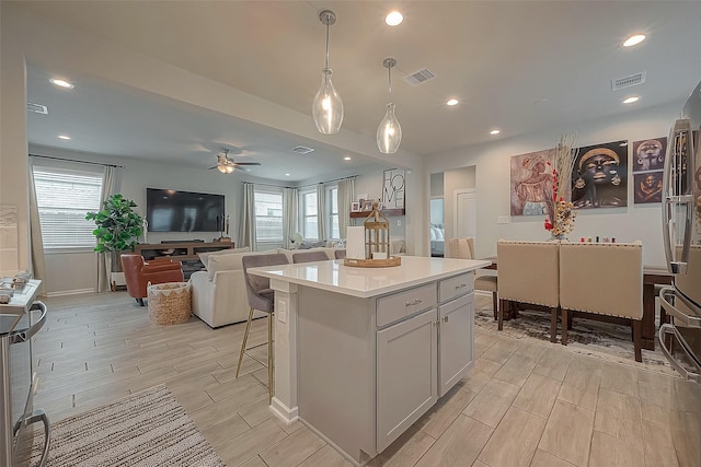 23611 Blackhaw Blossom Ln, Katy, TX 77493 - kitchen with visible vents, wood tiled floor, a ceiling fan, and a kitchen bar