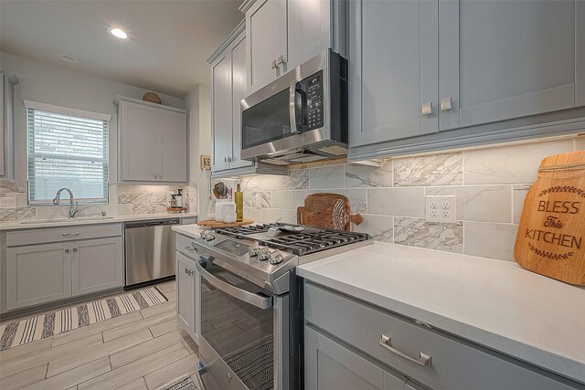 23611 Blackhaw Blossom Ln, Katy, TX 77493 - kitchen with appliances with stainless steel finishes, gray cabinetry, light countertops, and tasteful backsplash