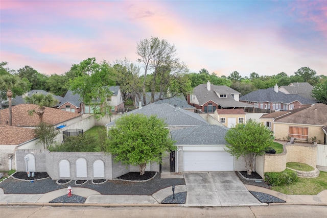 view of front of home with central AC, fence, concrete driveway, an attached garage, and a residential view