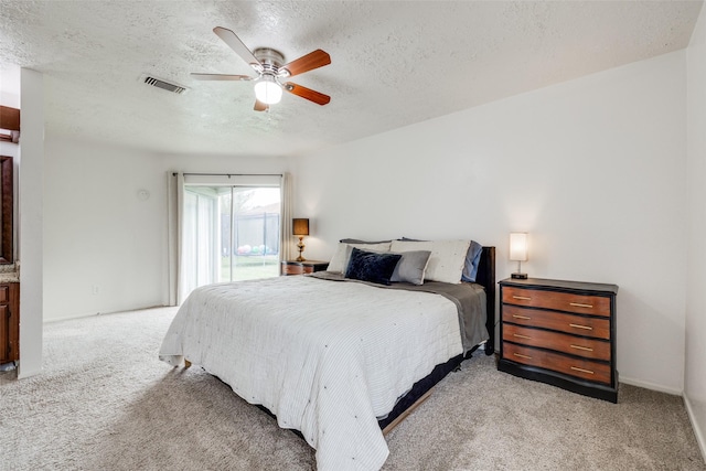 bedroom with ceiling fan, a textured ceiling, visible vents, access to outside, and light carpet