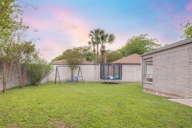 view of yard with a fenced backyard, a trampoline, and a playground