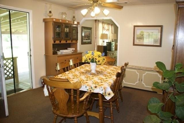 dining space featuring a ceiling fan, dark colored carpet, and a wealth of natural light