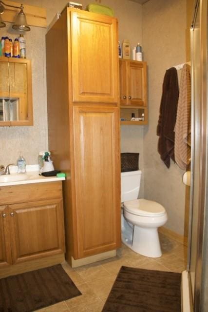 bathroom with tile patterned flooring, a shower with shower door, toilet, and vanity