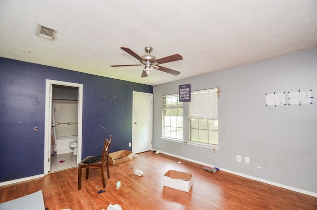 empty room with baseboards, ceiling fan, visible vents, and wood finished floors