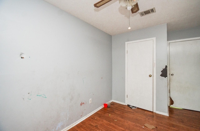 empty room with baseboards, ceiling fan, wood finished floors, and visible vents