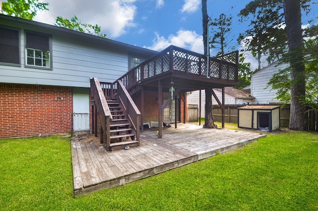 rear view of property featuring a lawn, a deck, fence, an outdoor structure, and a storage unit