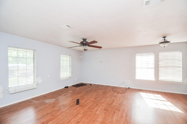 empty room featuring baseboards, ceiling fan, visible vents, and wood finished floors