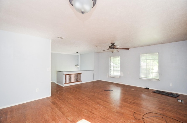 empty room featuring visible vents, ceiling fan, and wood finished floors