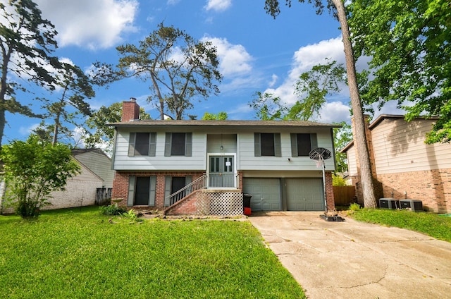 split foyer home with brick siding, an attached garage, a chimney, and a front yard