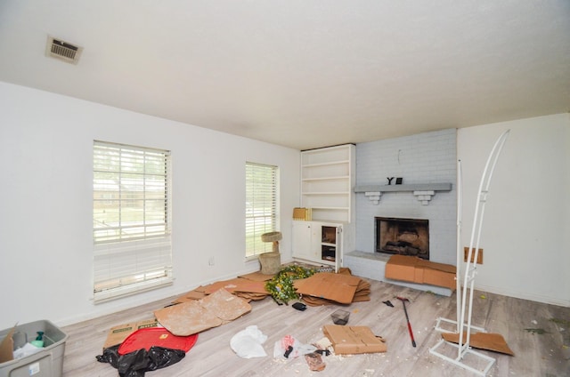 living room with baseboards, visible vents, wood finished floors, and a fireplace