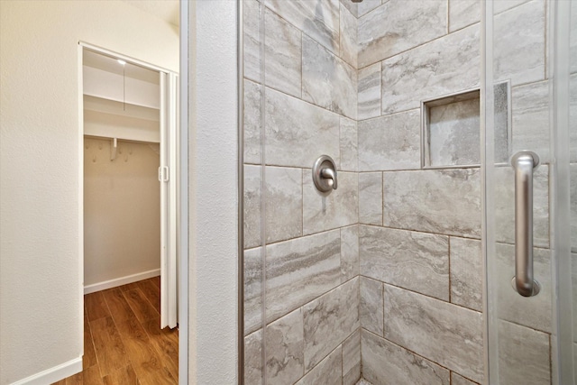 bathroom featuring baseboards, a shower stall, and wood finished floors