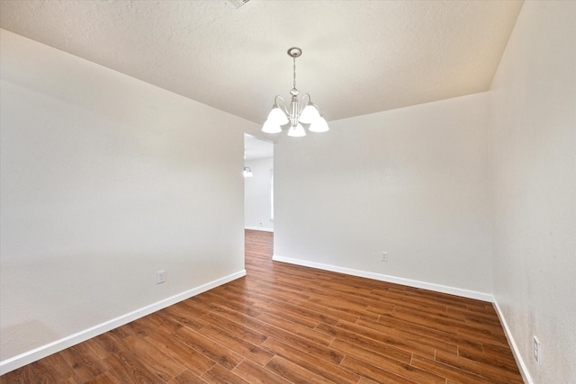 empty room with baseboards, a notable chandelier, and dark wood-style floors
