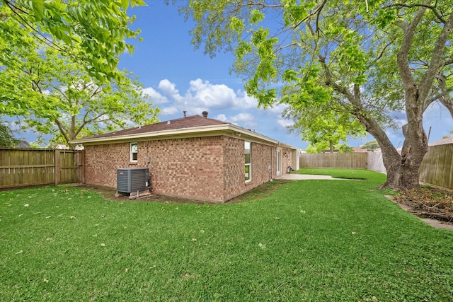 exterior space featuring brick siding, a fenced backyard, a lawn, and central AC