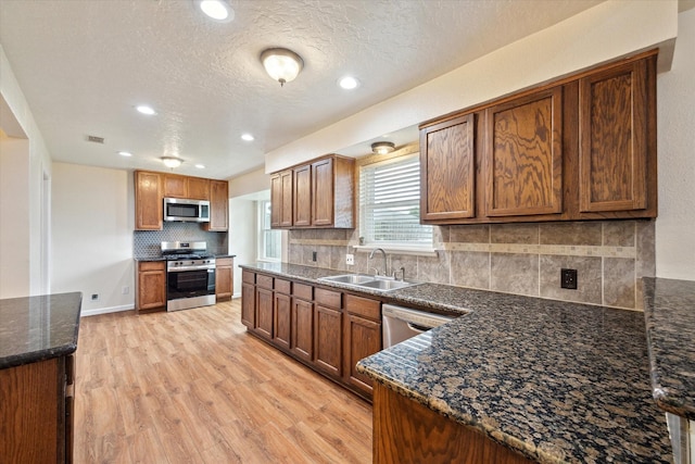 kitchen with visible vents, tasteful backsplash, a sink, light wood finished floors, and appliances with stainless steel finishes