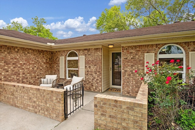 property entrance featuring brick siding and roof with shingles