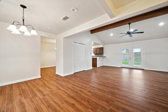 unfurnished living room featuring visible vents, wood finished floors, baseboards, ceiling fan with notable chandelier, and vaulted ceiling with beams