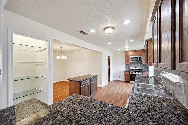 kitchen featuring backsplash, visible vents, a sink, light wood-style floors, and stainless steel appliances