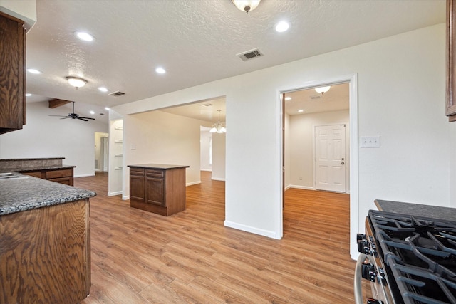 kitchen featuring a textured ceiling, visible vents, dark countertops, stainless steel gas range, and light wood-style flooring