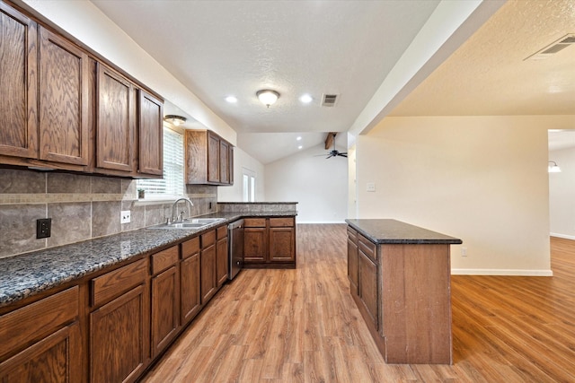 kitchen with a sink, backsplash, light wood-type flooring, stainless steel dishwasher, and visible vents