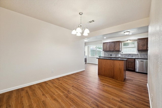 kitchen featuring visible vents, dark countertops, a sink, dishwasher, and a notable chandelier