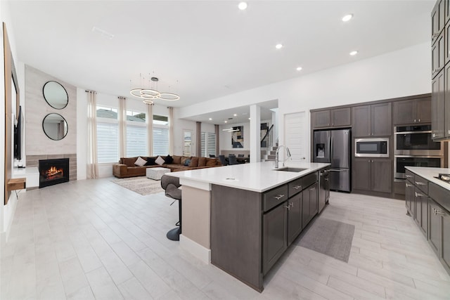 kitchen with a sink, light countertops, stainless steel appliances, and open floor plan