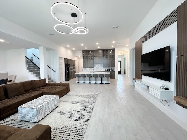 living area with visible vents, recessed lighting, light wood-style flooring, and stairs