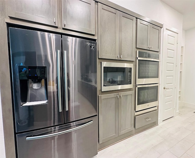 kitchen with baseboards, gray cabinetry, and stainless steel appliances