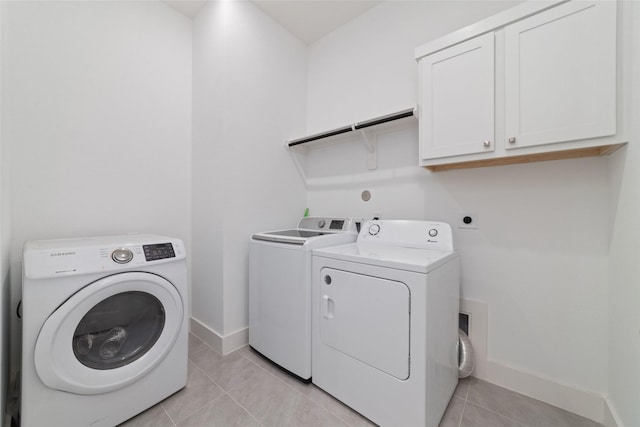 laundry area with light tile patterned floors, baseboards, washing machine and dryer, and cabinet space