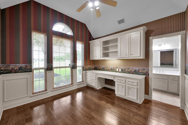 19731 Stone Lake Dr, Tomball, TX 77377 - unfurnished office with wallpapered walls, built in desk, vaulted ceiling, ceiling fan, and dark wood-type flooring