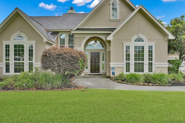 19731 Stone Lake Dr, Tomball, TX 77377 - view of front of house featuring stucco siding, a front lawn, roof with shingles, and a chimney