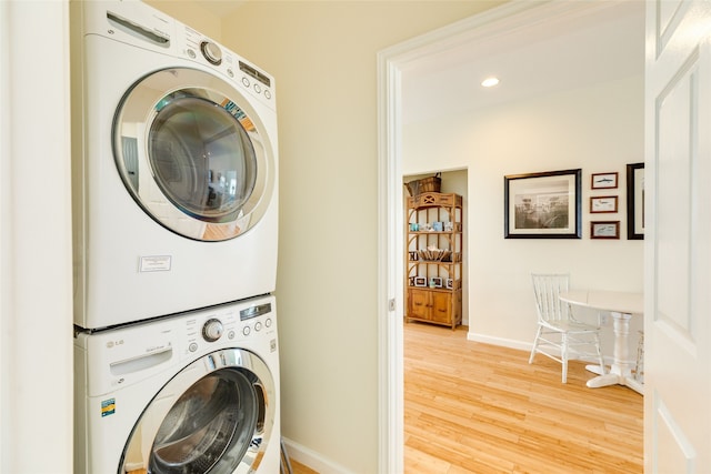 laundry room with laundry area, stacked washer and clothes dryer, wood finished floors, baseboards, and recessed lighting
