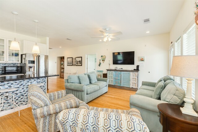 living area with light wood-style floors, a ceiling fan, a toaster, and visible vents