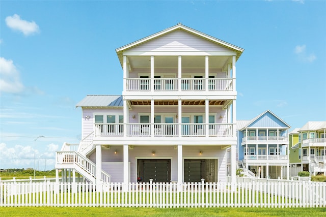back of property featuring stairs, a fenced front yard, and a balcony