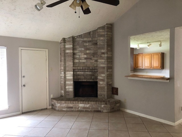 unfurnished living room with a ceiling fan, a textured ceiling, a brick fireplace, lofted ceiling, and light tile patterned flooring