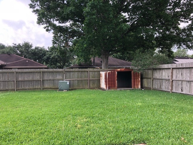 view of yard featuring an outbuilding, a fenced backyard, and a shed