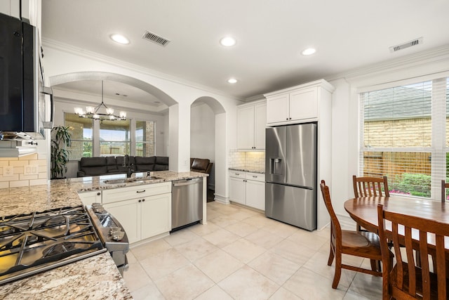 kitchen with a sink, arched walkways, stainless steel appliances, visible vents, and ornamental molding