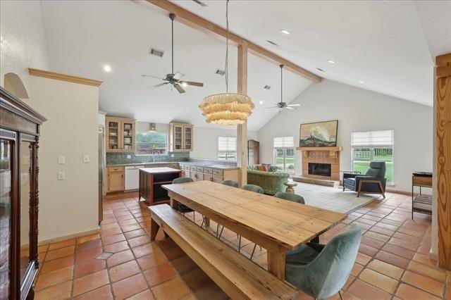 dining area featuring beam ceiling, a fireplace, high vaulted ceiling, a ceiling fan, and visible vents
