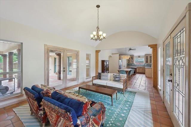 living area with ceiling fan with notable chandelier, french doors, light tile patterned flooring, and lofted ceiling