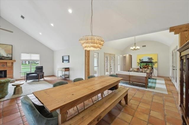 dining room with a notable chandelier, a fireplace, high vaulted ceiling, light tile patterned floors, and visible vents