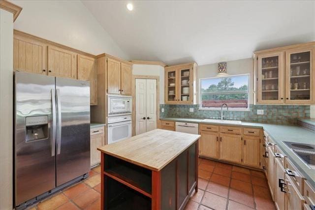kitchen with a sink, light brown cabinets, decorative backsplash, and white appliances