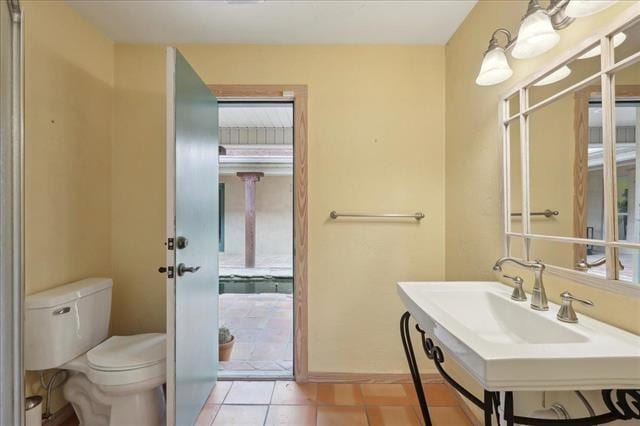 half bathroom featuring baseboards, tile patterned floors, and toilet