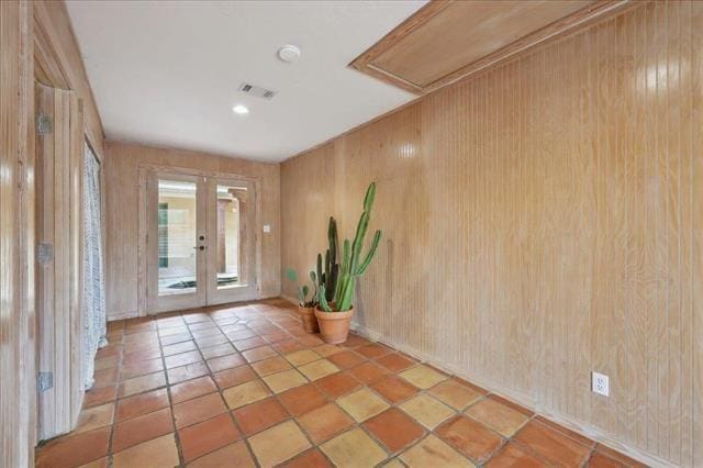 tiled entryway featuring visible vents, wooden walls, and french doors