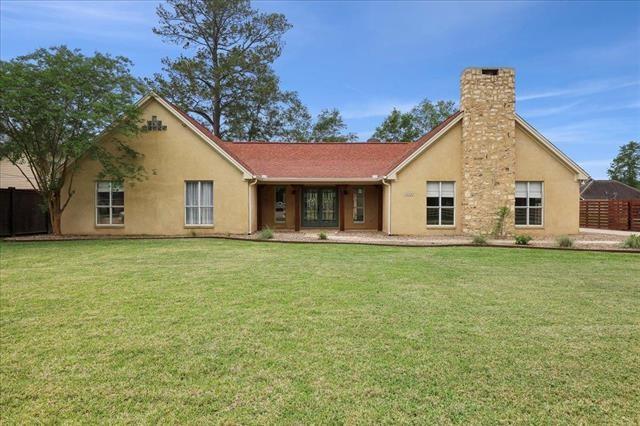 rear view of property with a yard, fence, a chimney, and stucco siding