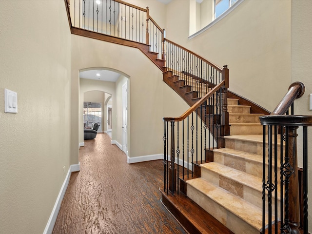 17306 Lake Chelan Ln, Humble, TX 77346 - stairway with arched walkways, baseboards, wood finished floors, and a towering ceiling