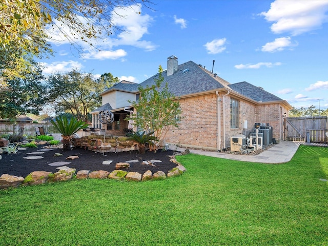 17306 Lake Chelan Ln, Humble, TX 77346 - rear view of house with a chimney, a lawn, brick siding, a fenced backyard, and a shingled roof