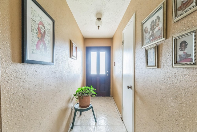 doorway featuring a textured ceiling and a textured wall