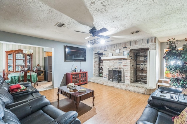 living area with visible vents, a textured ceiling, ceiling fan, and wood finished floors