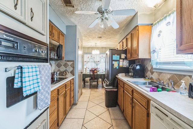 kitchen with visible vents, a healthy amount of sunlight, white appliances, a sink, and backsplash