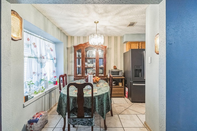 dining area featuring an inviting chandelier, light tile patterned floors, a textured wall, and a textured ceiling